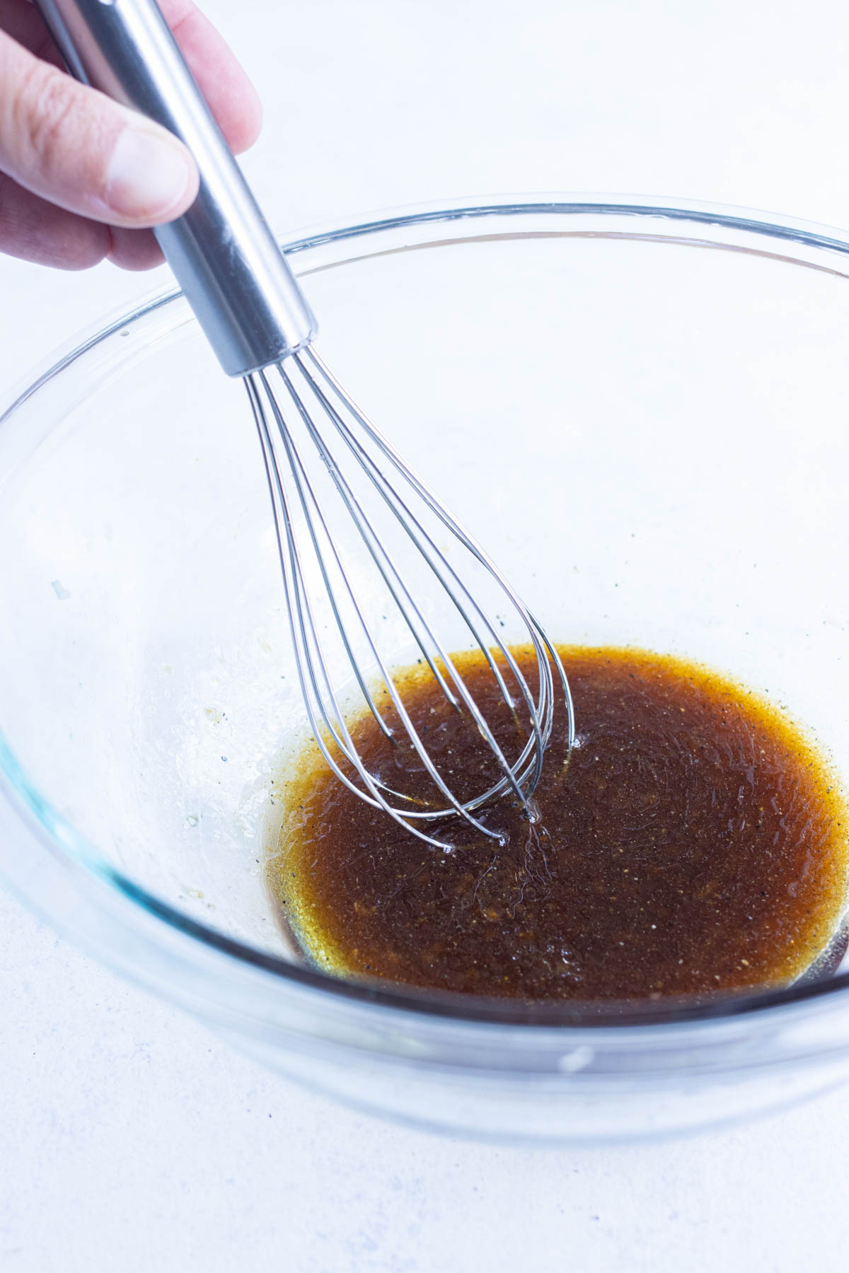 A marinade is whisked in a glass bowl.