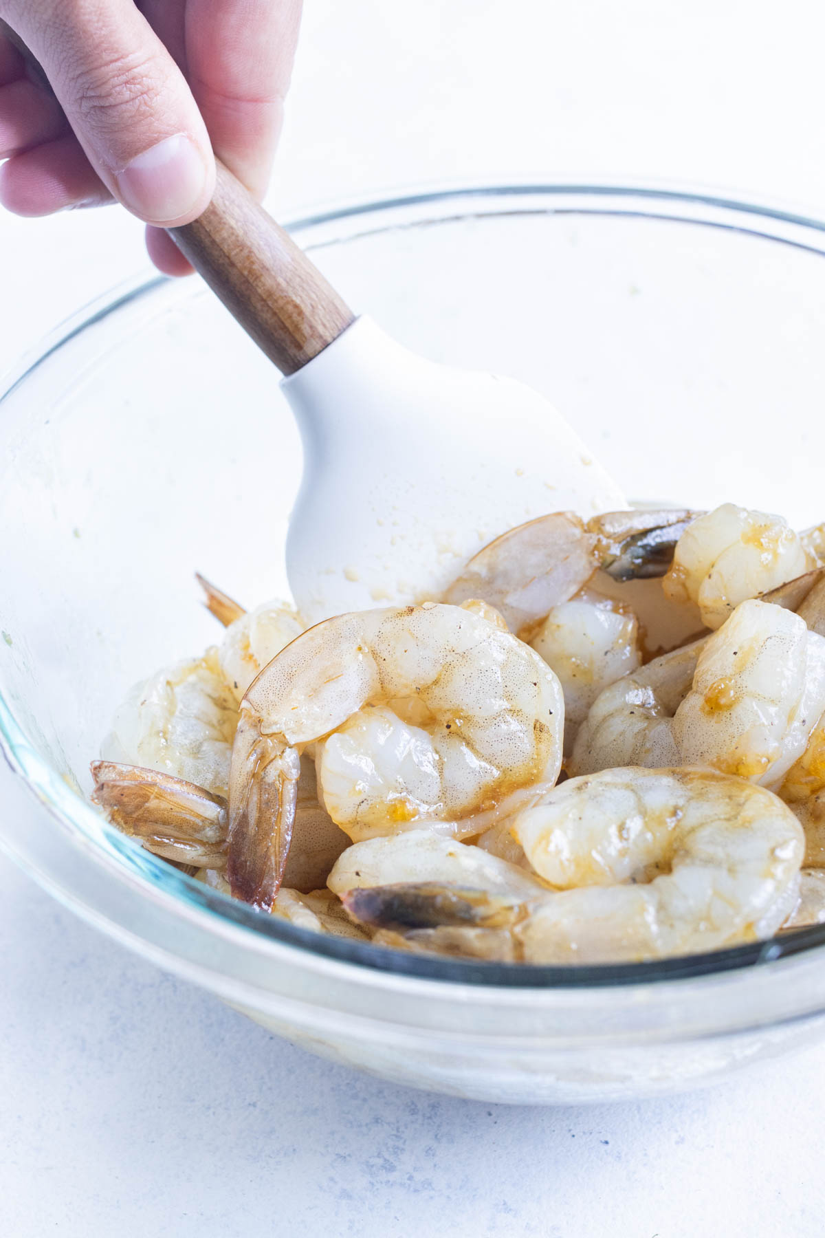 Shrimp is tossed with a marinade.