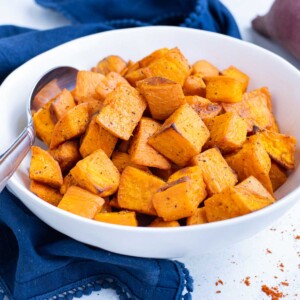 Sweet potato cubes are in a white bowl with a spoon.