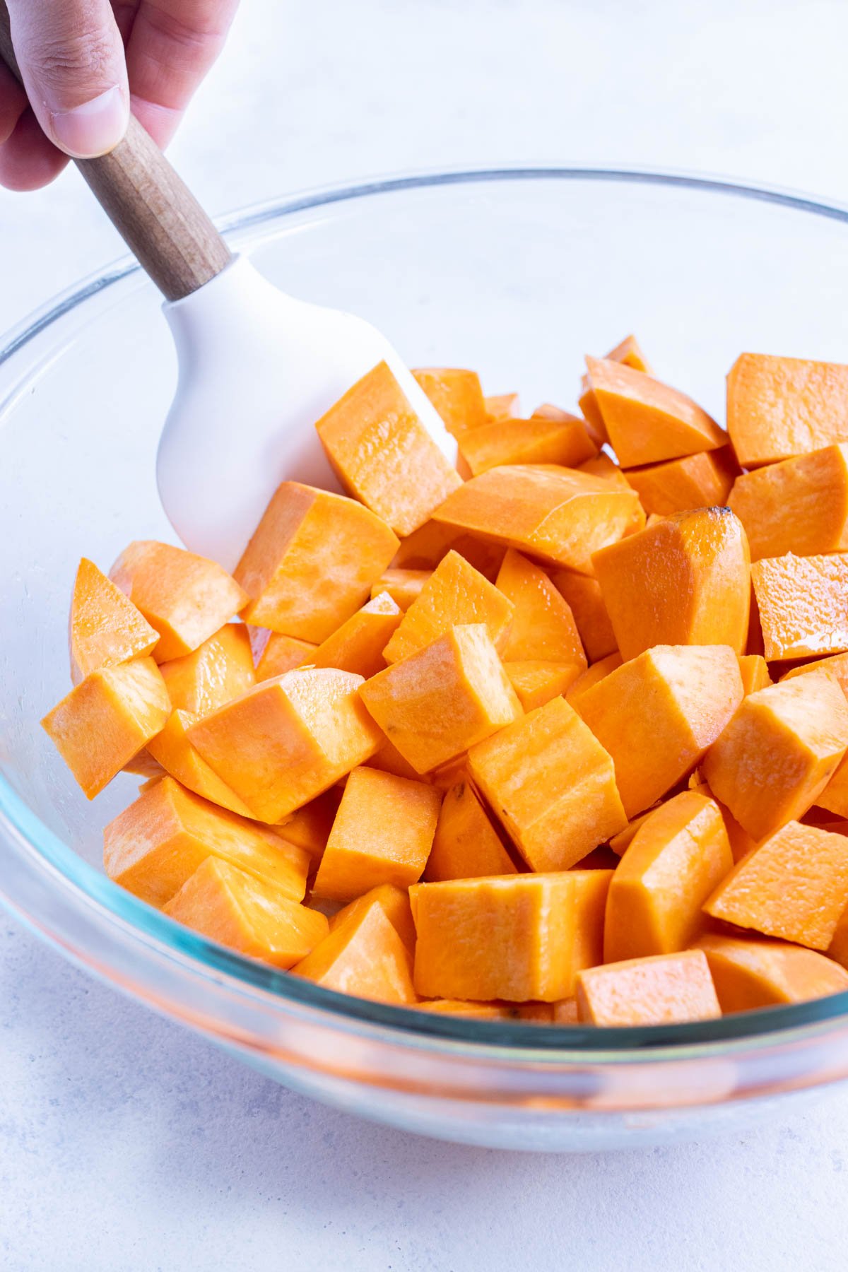 Sweet potatoes are tossed with oil.