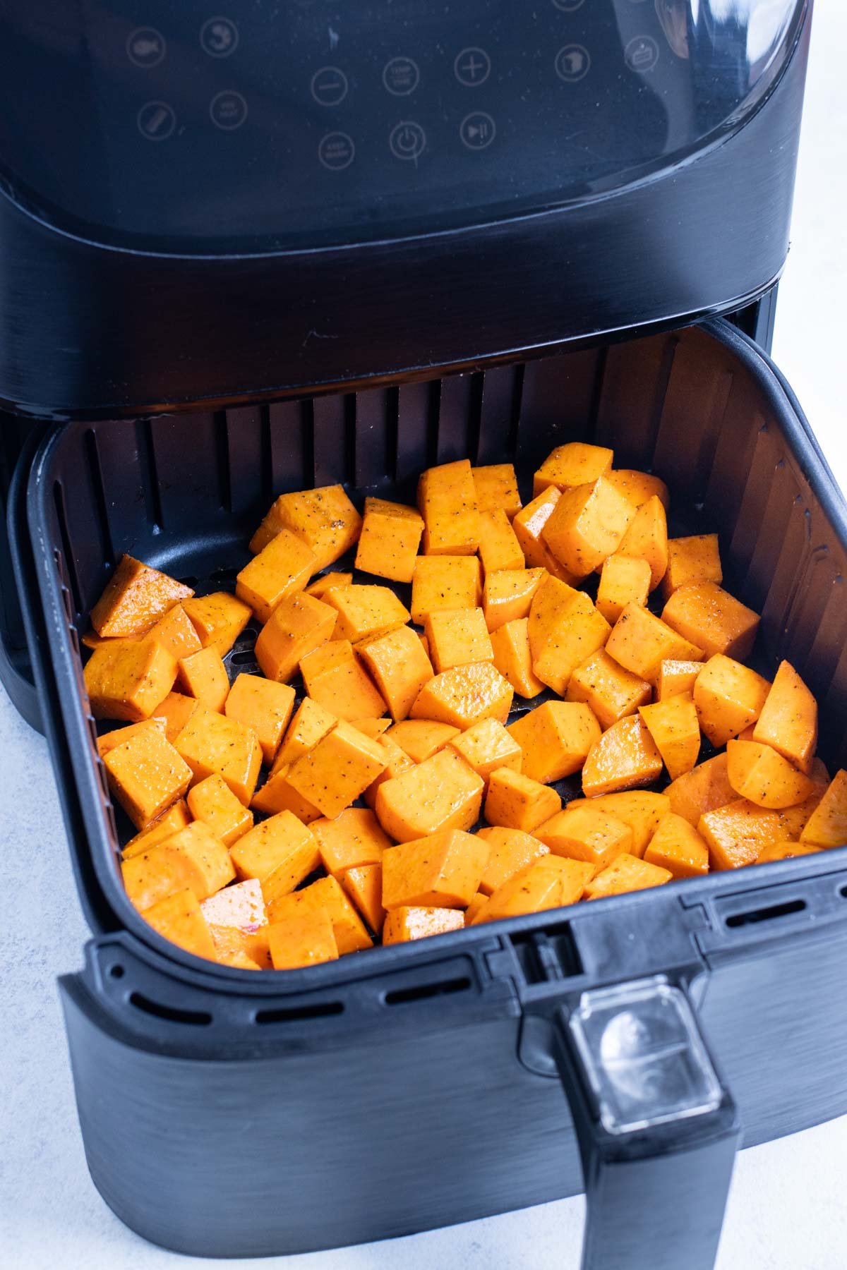 Sweet potatoes are in a single row in an air fryer.