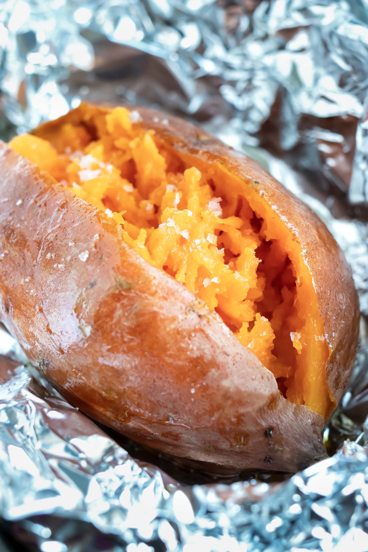 A baked sweet potato that has been wrapped in foil and baked in the oven.