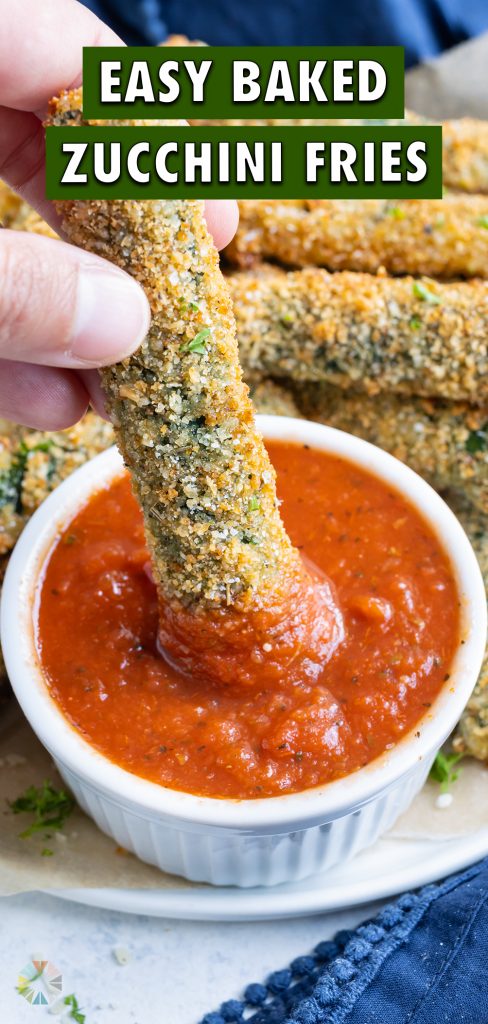 Parmesan zucchini fries dipped in sauce on a white plate.