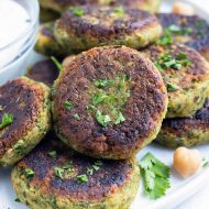 Vegan homemade falafel with fresh parsley and chickpeas are plated with a greek yogurt sauce.