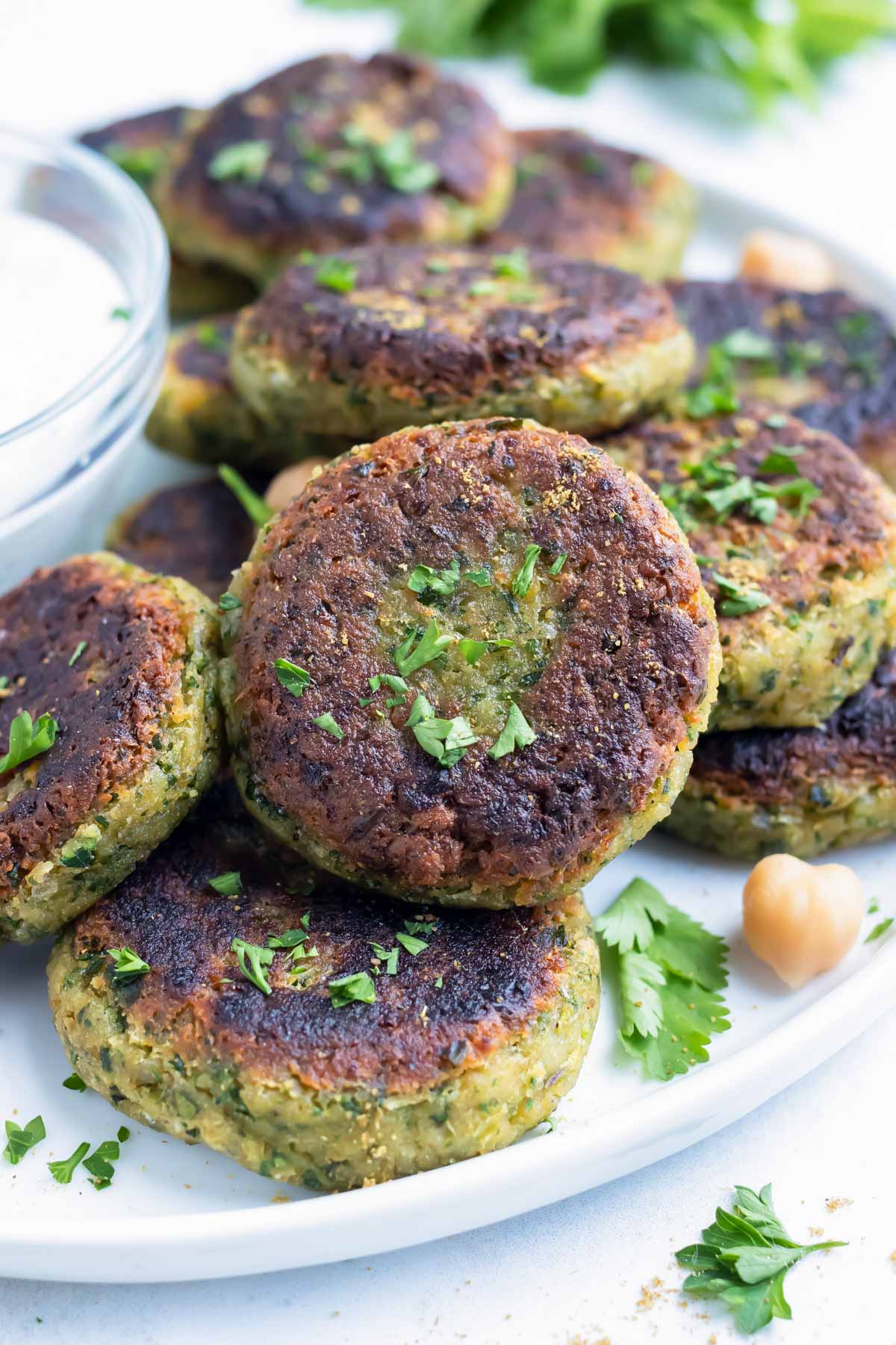 Vegan homemade falafel with fresh parsley and chickpeas are plated with a greek yogurt sauce.