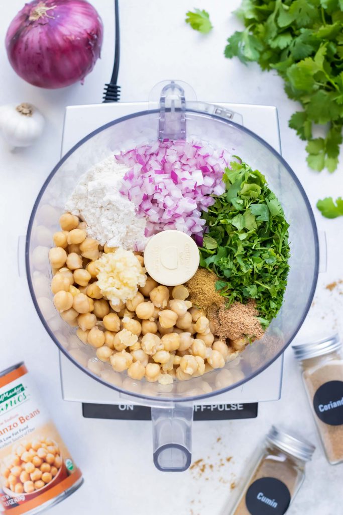 Chickpeas, herbs, and spices added to a food processor for gluten-free falafel