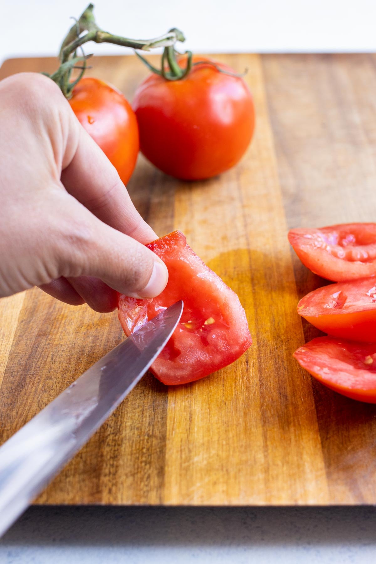 A knife carefully removes the seeds from the tomato flesh.