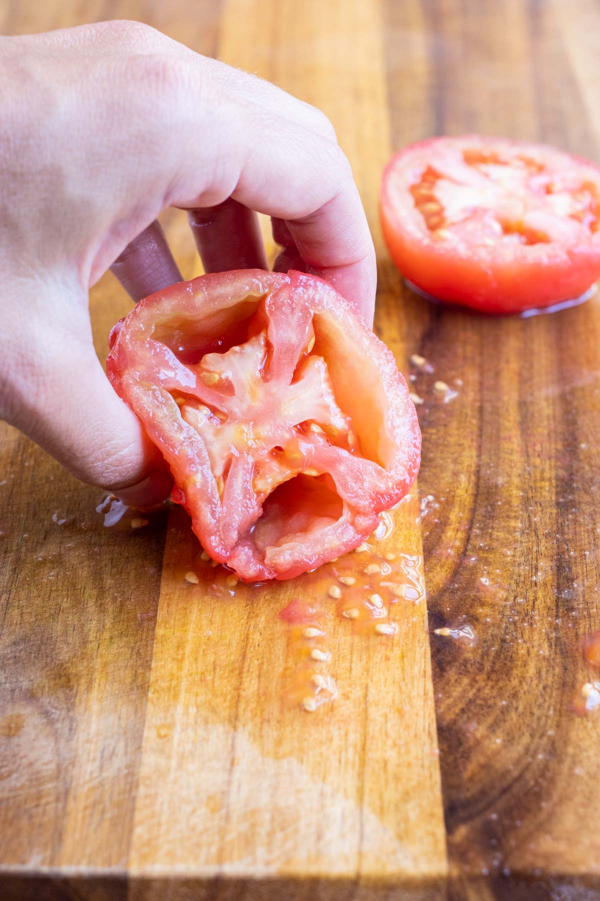 You can remove the seeds of a tomato by squeezing them out.