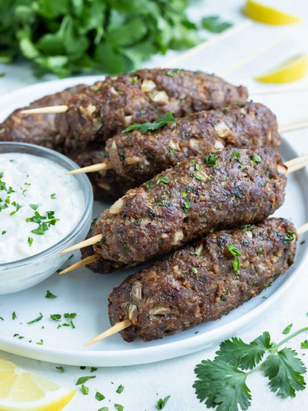 Lamb Kofta is served on a white plate with Tzatziki sauce.