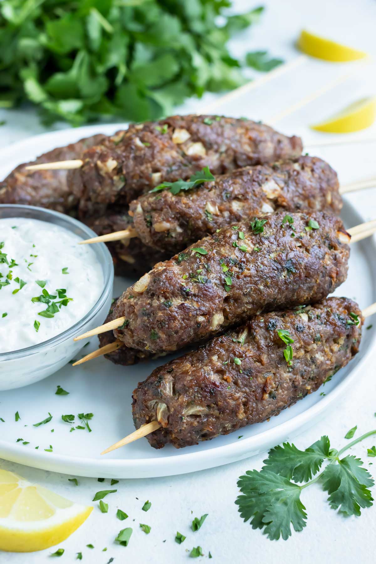 Lamb Kofta is served on a white plate with Tzatziki sauce.