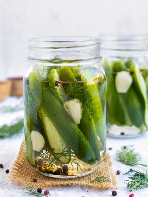 Two jars of overnight refrigerator dill pickles on a counter.