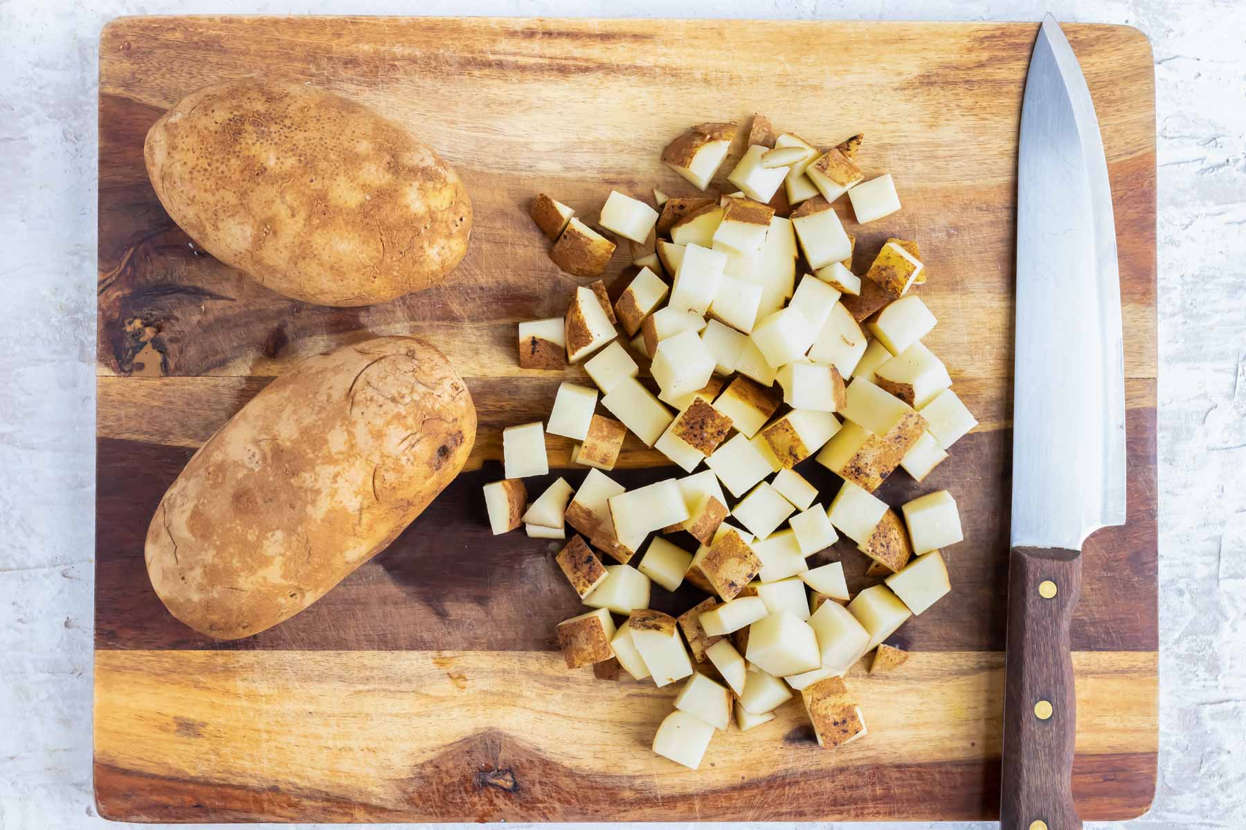 A potato is diced on a cutting board.