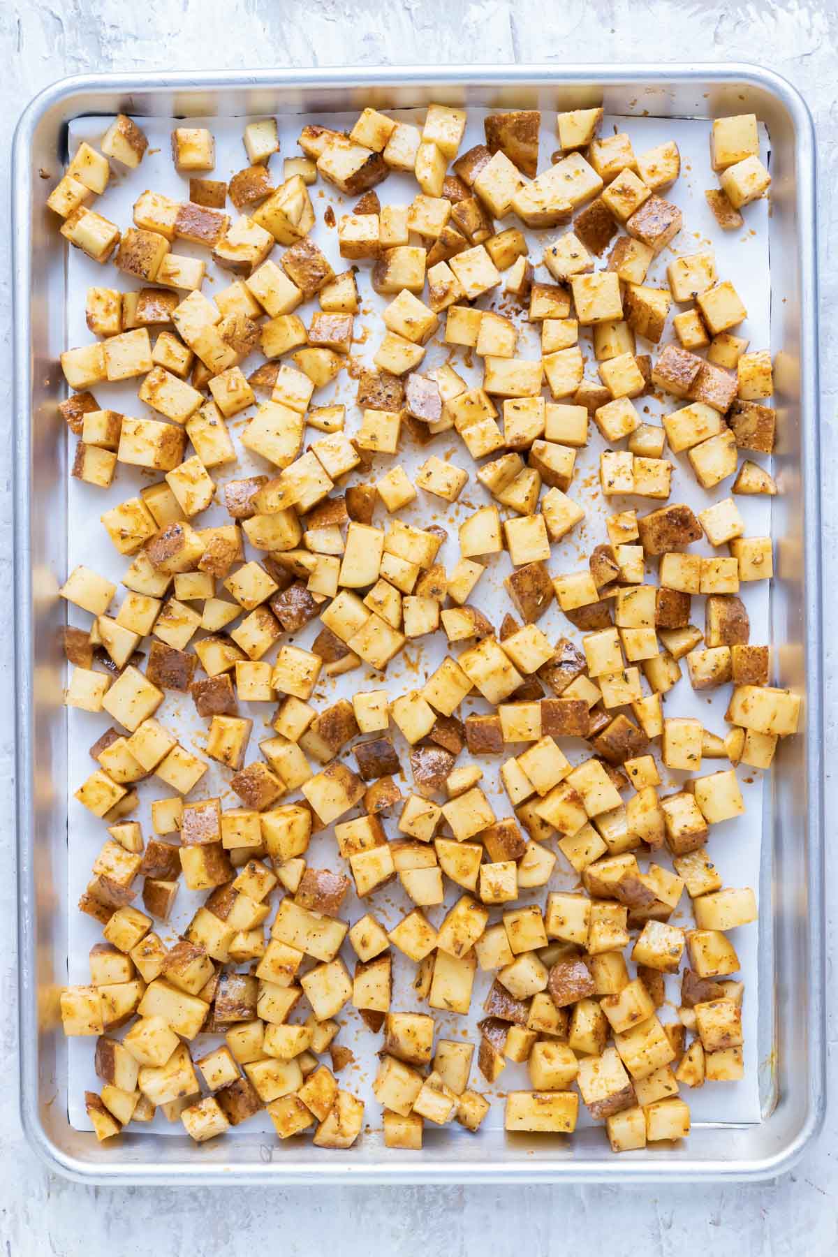 A sheet pan full of seasoned potato cubes.
