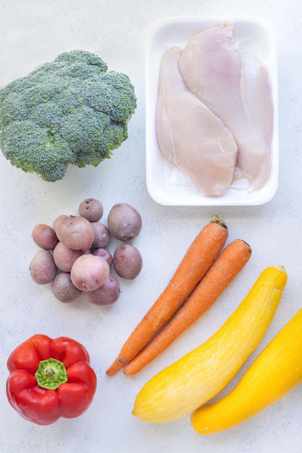 Chicken, broccoli, potatoes, carrots, squash, and red peppers are the ingredients for this dish.