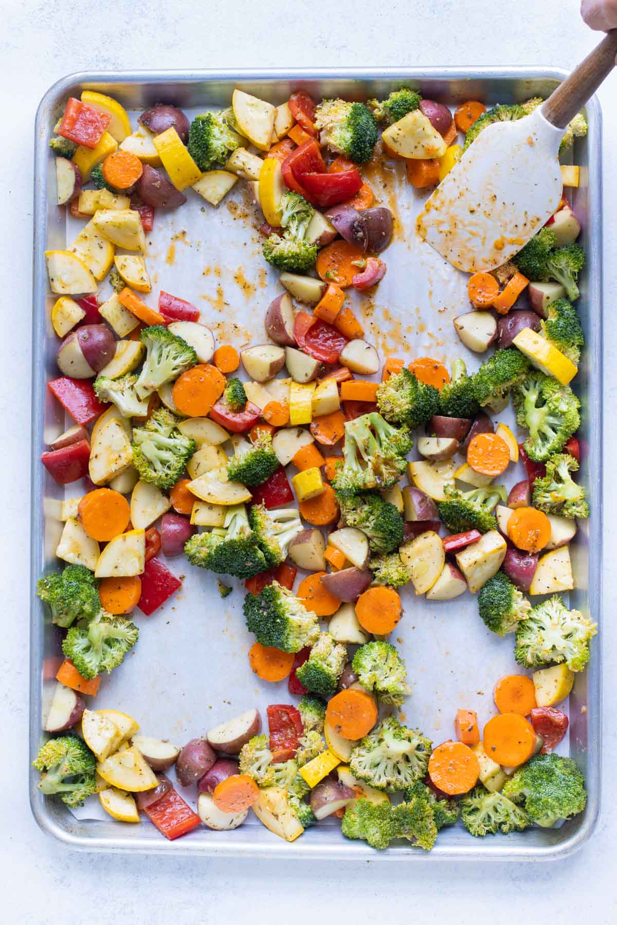 Holes are created in a tray of vegetables for chicken breasts.