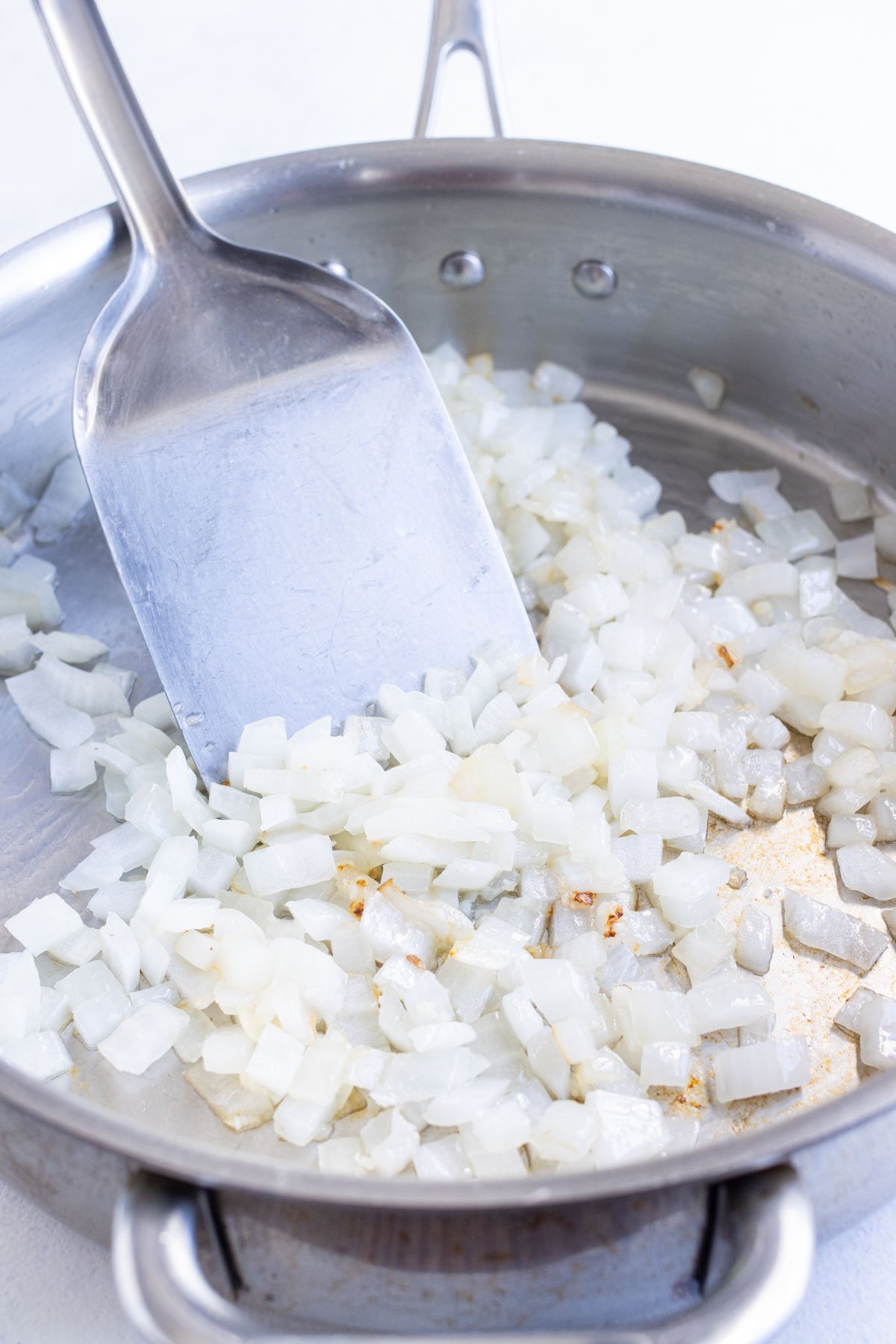 Onions and garlic are cooked in a skillet.