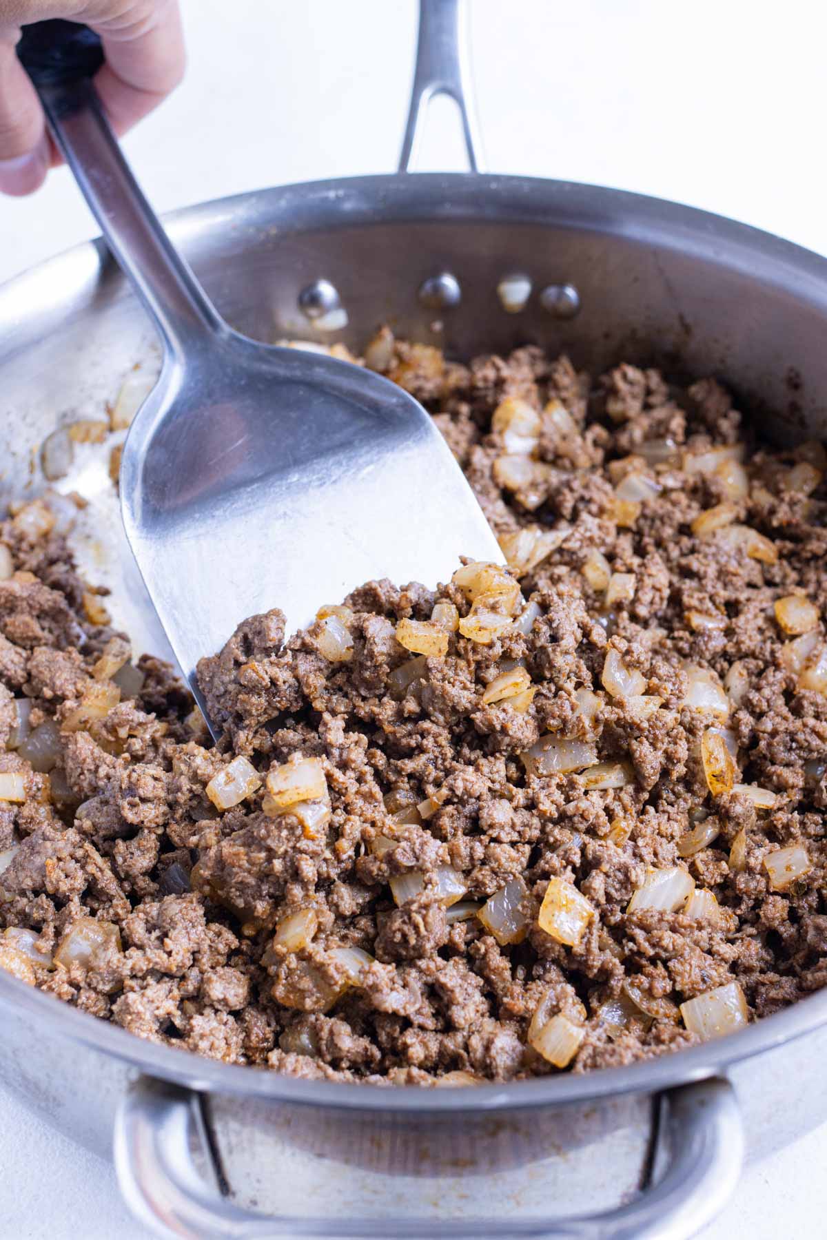 Seasoned ground beef is cooked in a skillet.