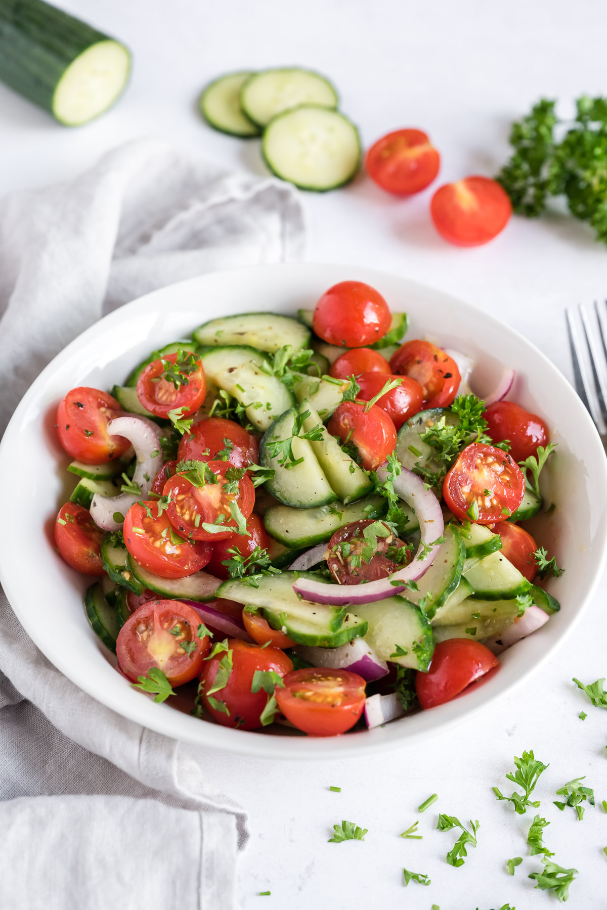 Vegetarian cucumber tomato salad in a white bowl.