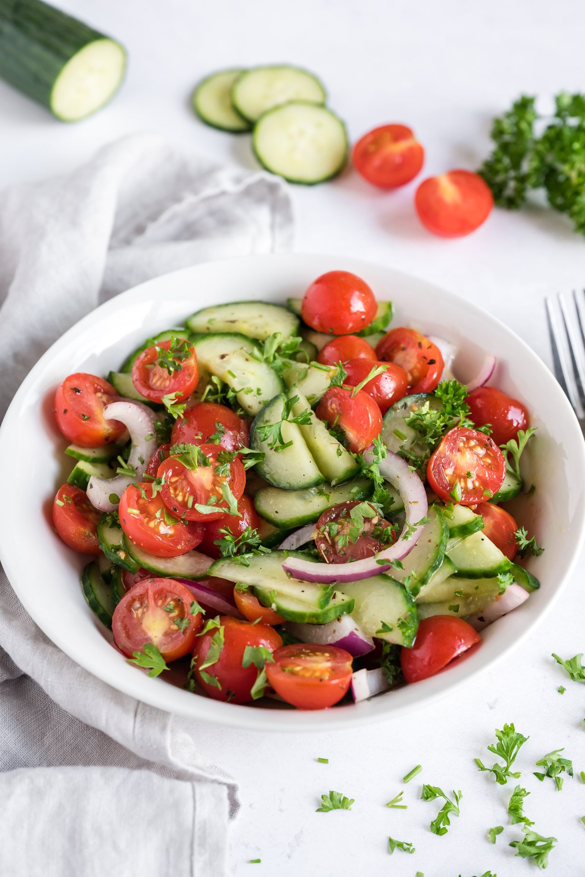 Vegetarian cucumber tomato salad in a white bowl.