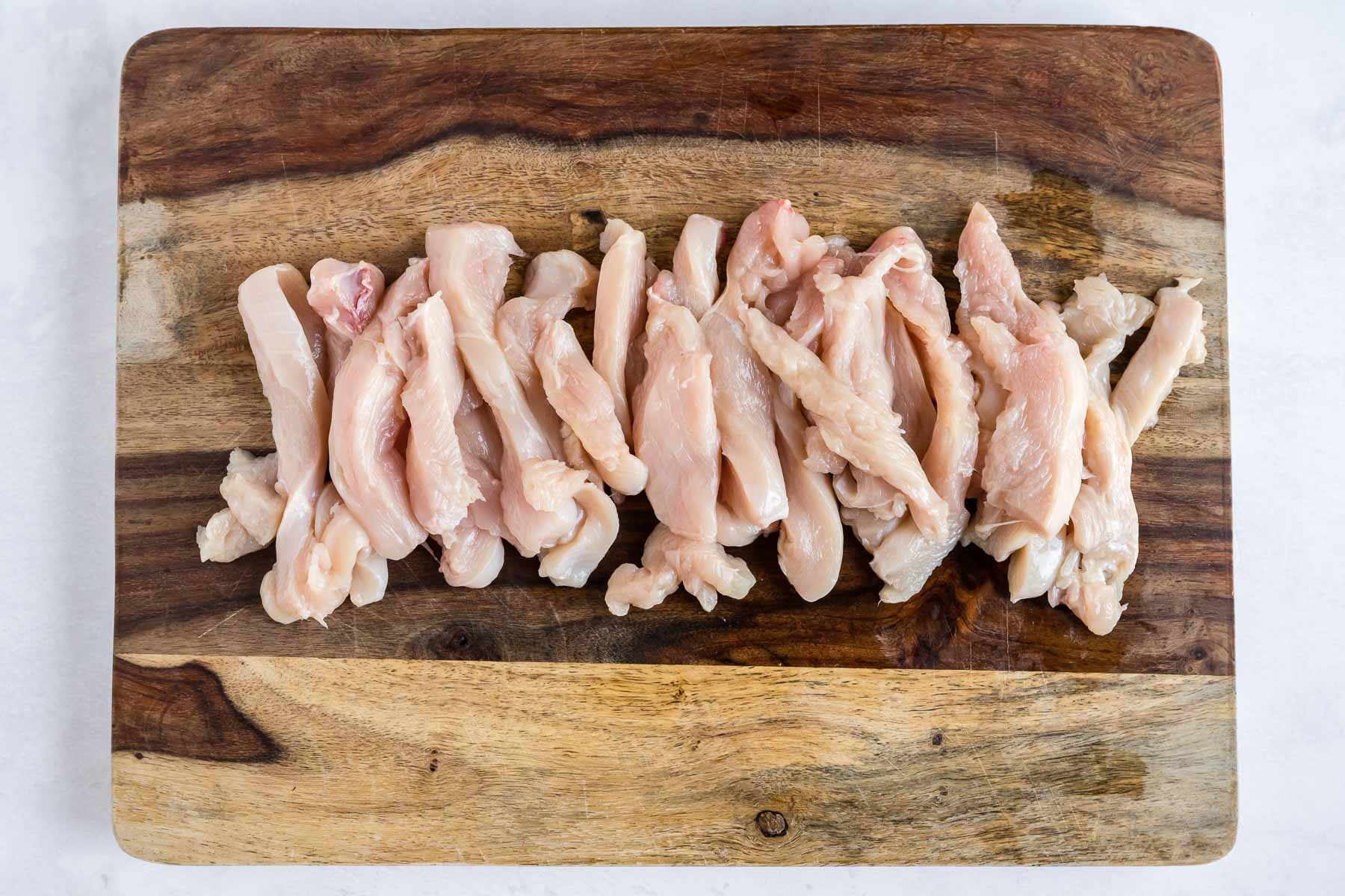 Strips of chicken on a cutting board.