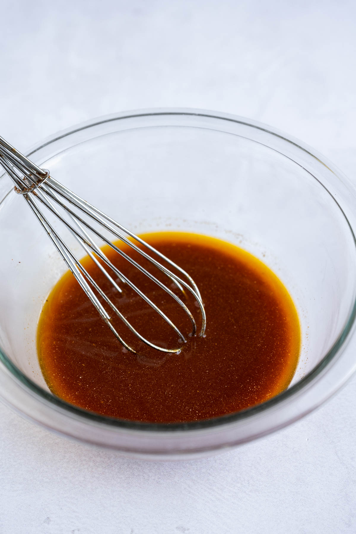 A whisk stirs a marinade with fajita seasoning.