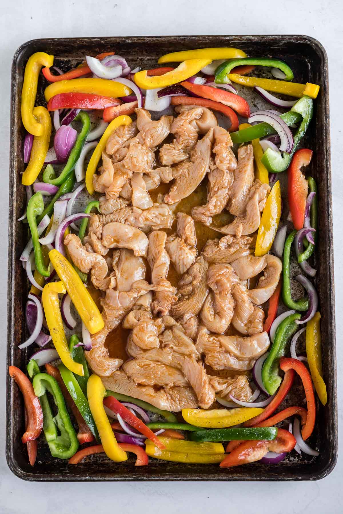Chicken and vegetables are on a sheet pan.