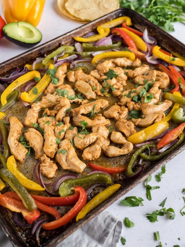 Chicken and veggies are cooked on a sheet pan together.