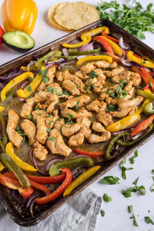 Chicken and veggies are cooked on a sheet pan together.