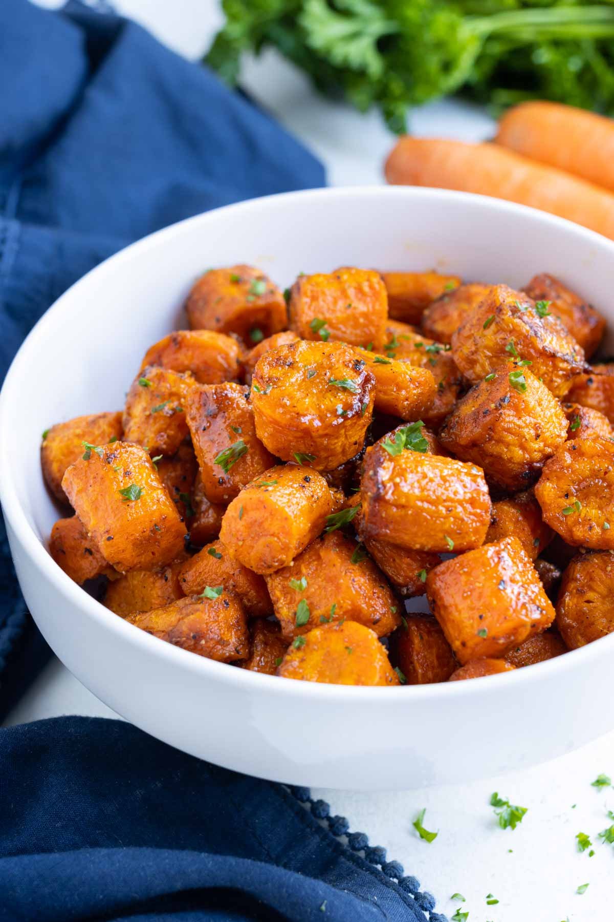 A white bowl has seasoned carrots cooked in the air fryer.