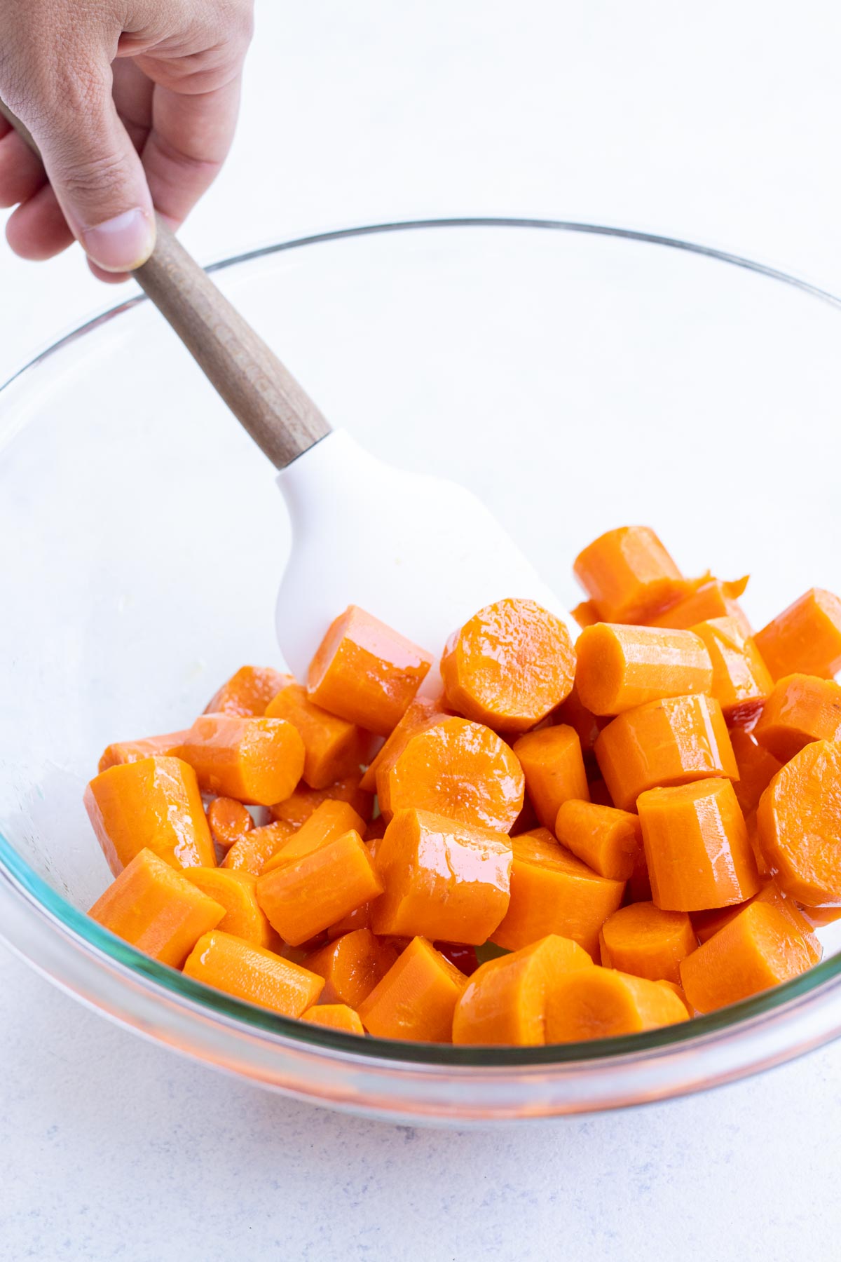 Sliced carrots are covered in oil in a bowl.