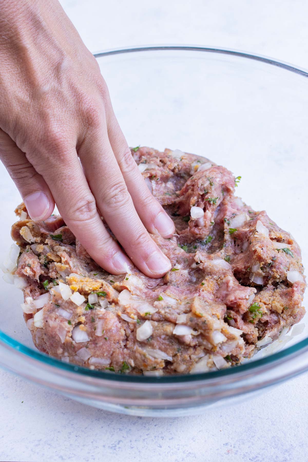 Meatloaf ingredients are mixed by hand.