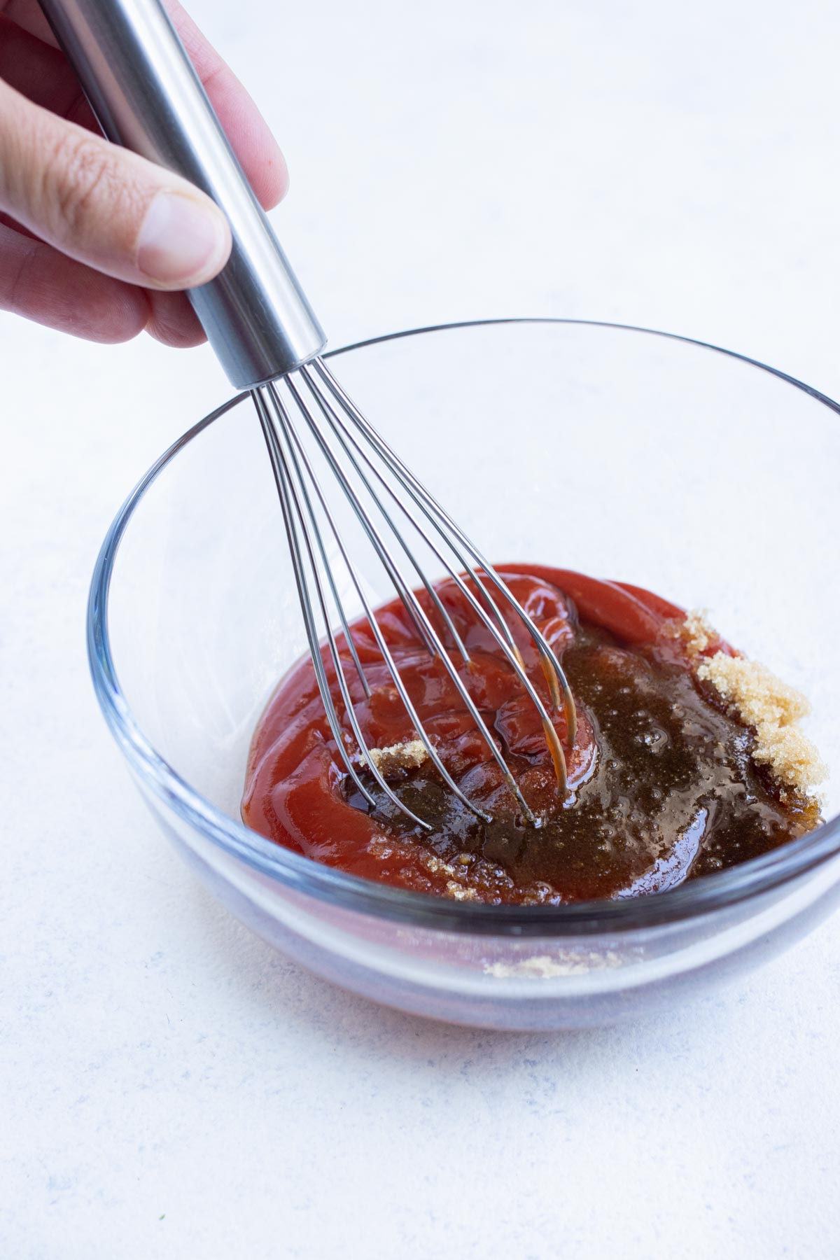 Ketchup, brown sugar, and Worcestershire is whisked in a bowl.
