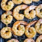 Air fryer shrimp are in a basket after being cooked.