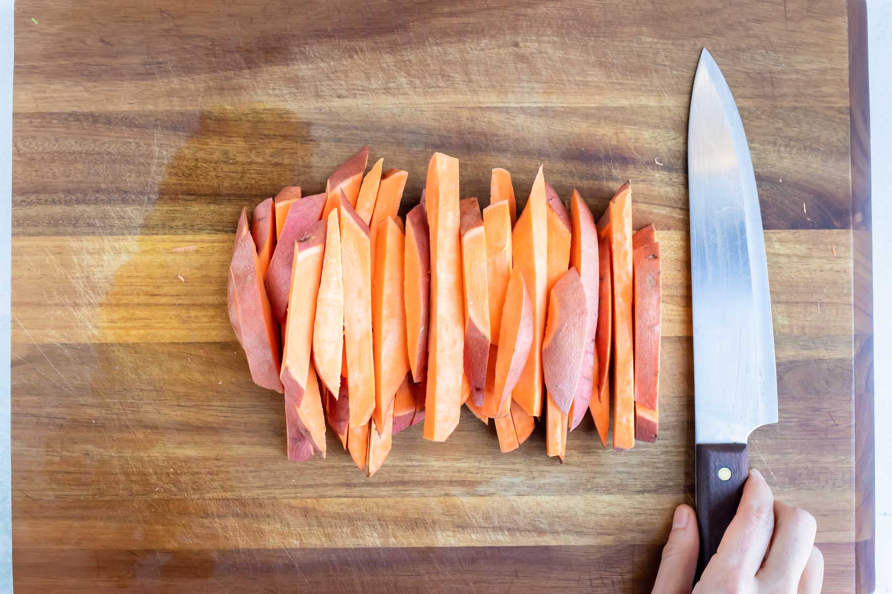Sweet potatoes are cut into slices on a cutting board.