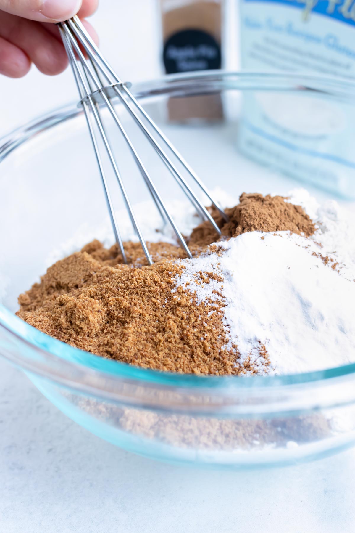 Flour, sugar, and spices are mixed in a glass bowl.