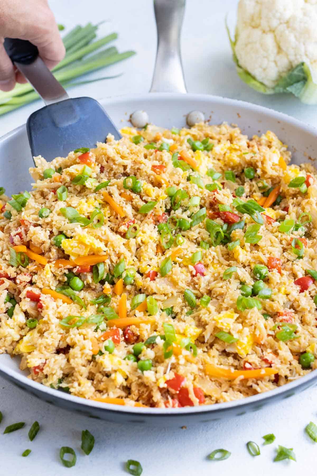 A skillet full of cauliflower fried rice is healthy and easy to make.