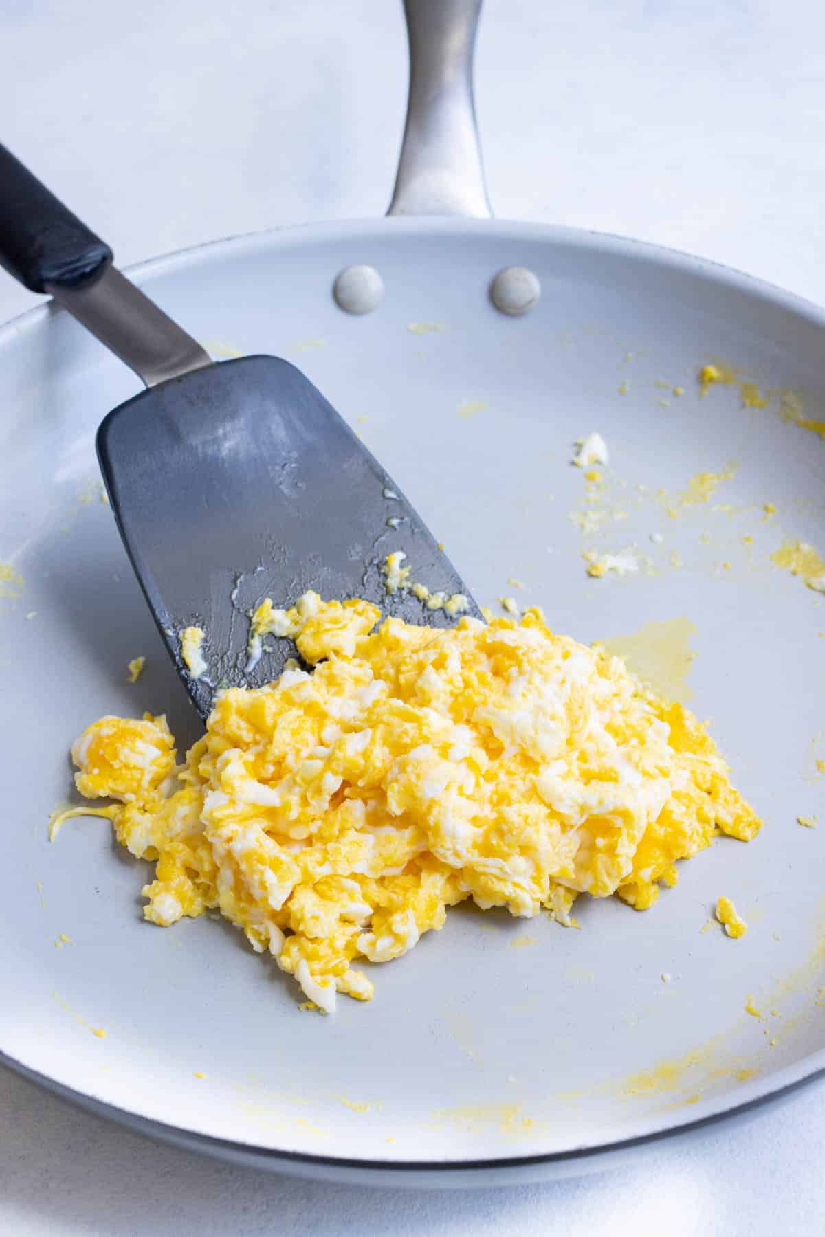 Eggs are scrambled in a large skillet.
