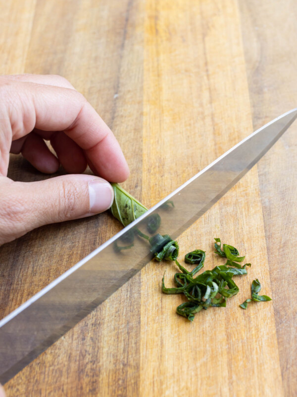 A roll of basil is thinly sliced.