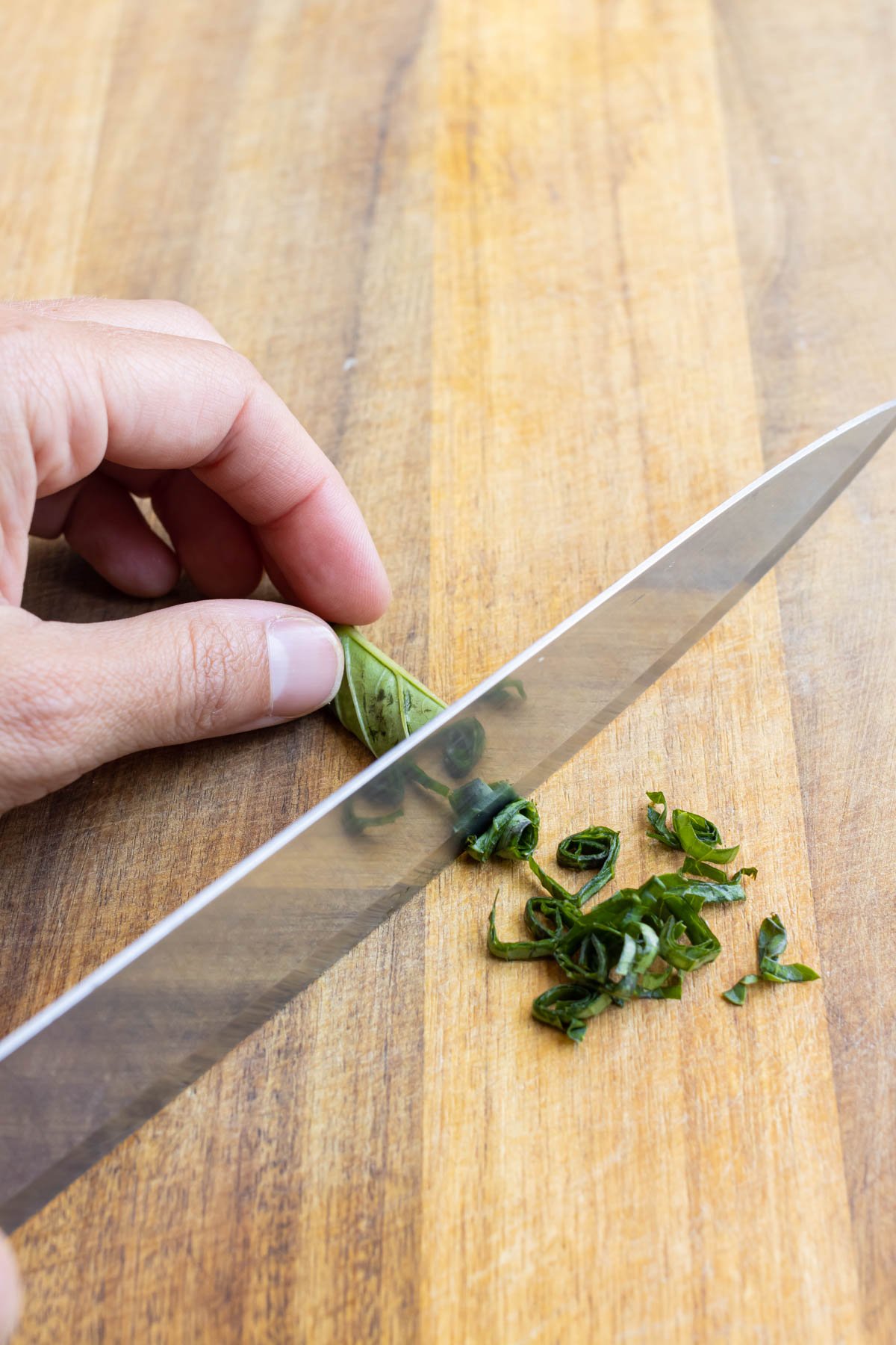 A roll of basil is thinly sliced.