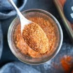 A small spoon scooping up a serving of a DIY chili seasoning mix made with chili powder and cumin.