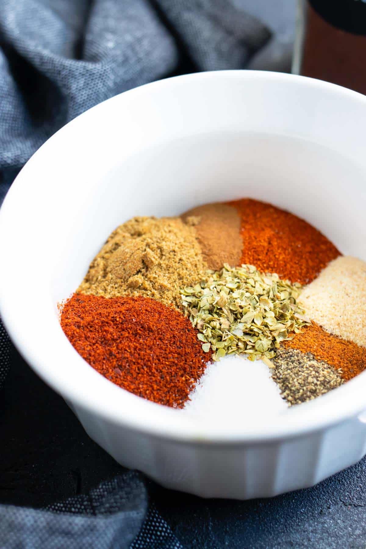 Spices in a white bowl showing how to make homemade chili seasoning.