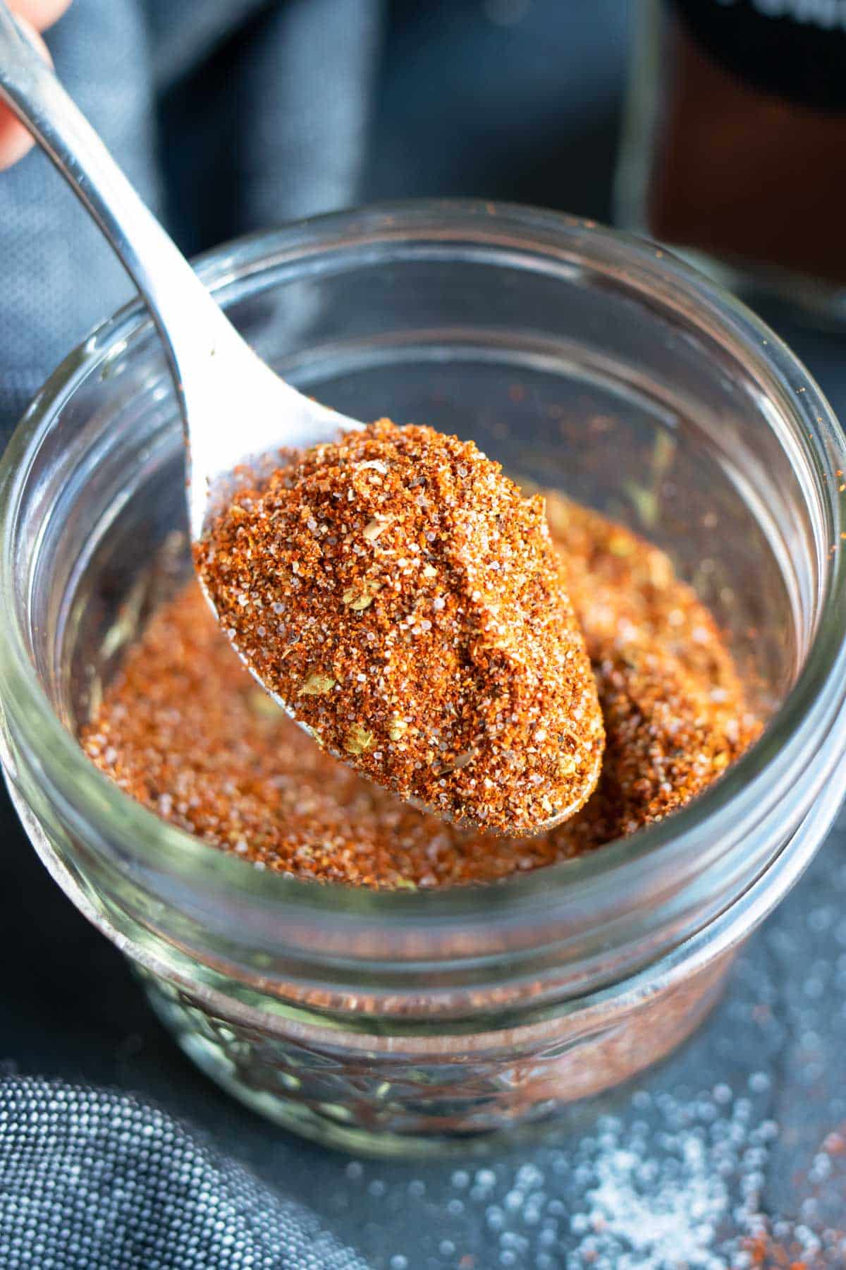 A spoon picking up chili seasoning mix to put into a homemade Instant Pot chili recipe.