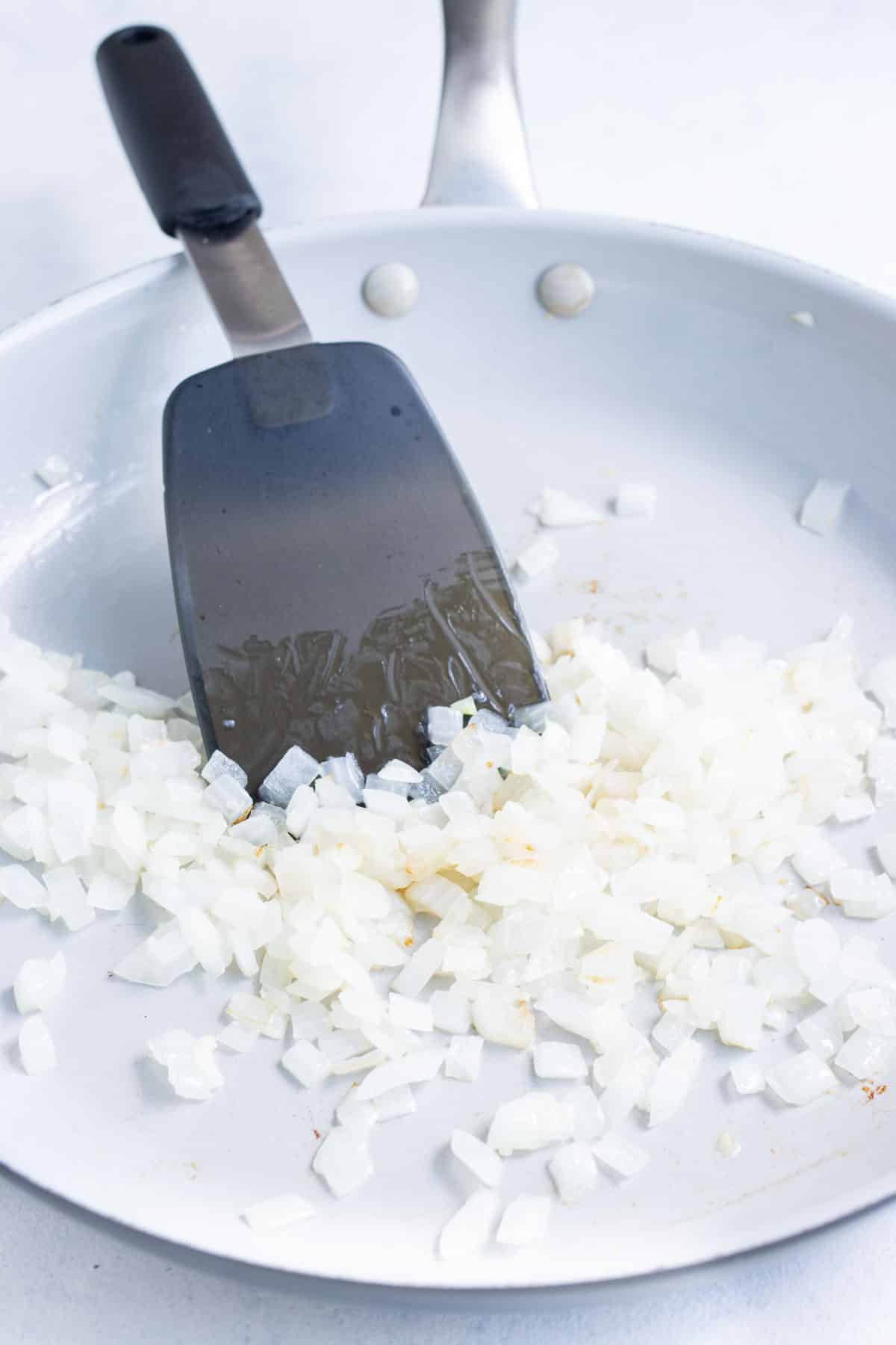Onion and garlic are cooked in a skillet.
