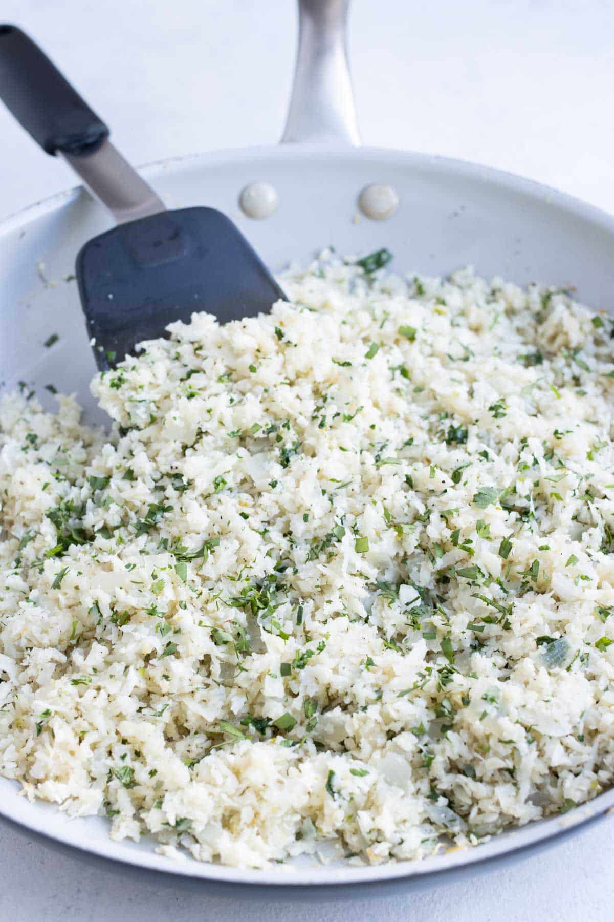 A skillet is full of healthy cilantro lime cauliflower rice.