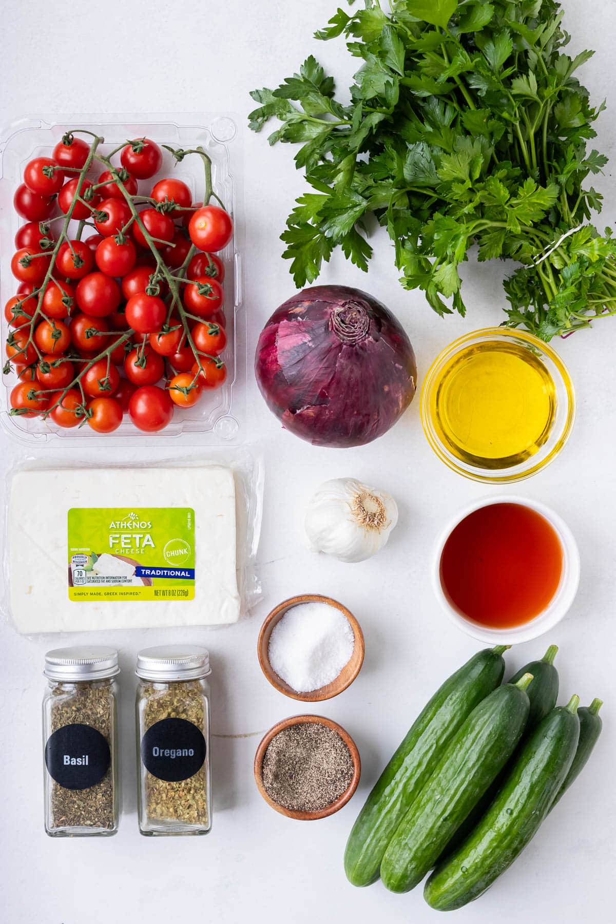 The ingredients for an easy Greek cucumber tomato and feta salad are laid out on a counter.