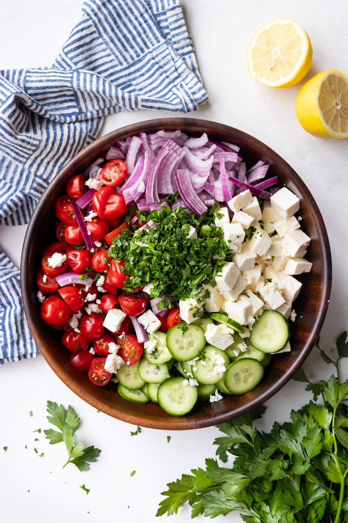 The ingredients for a Greek cucumber tomato salad are placed in a bowl.