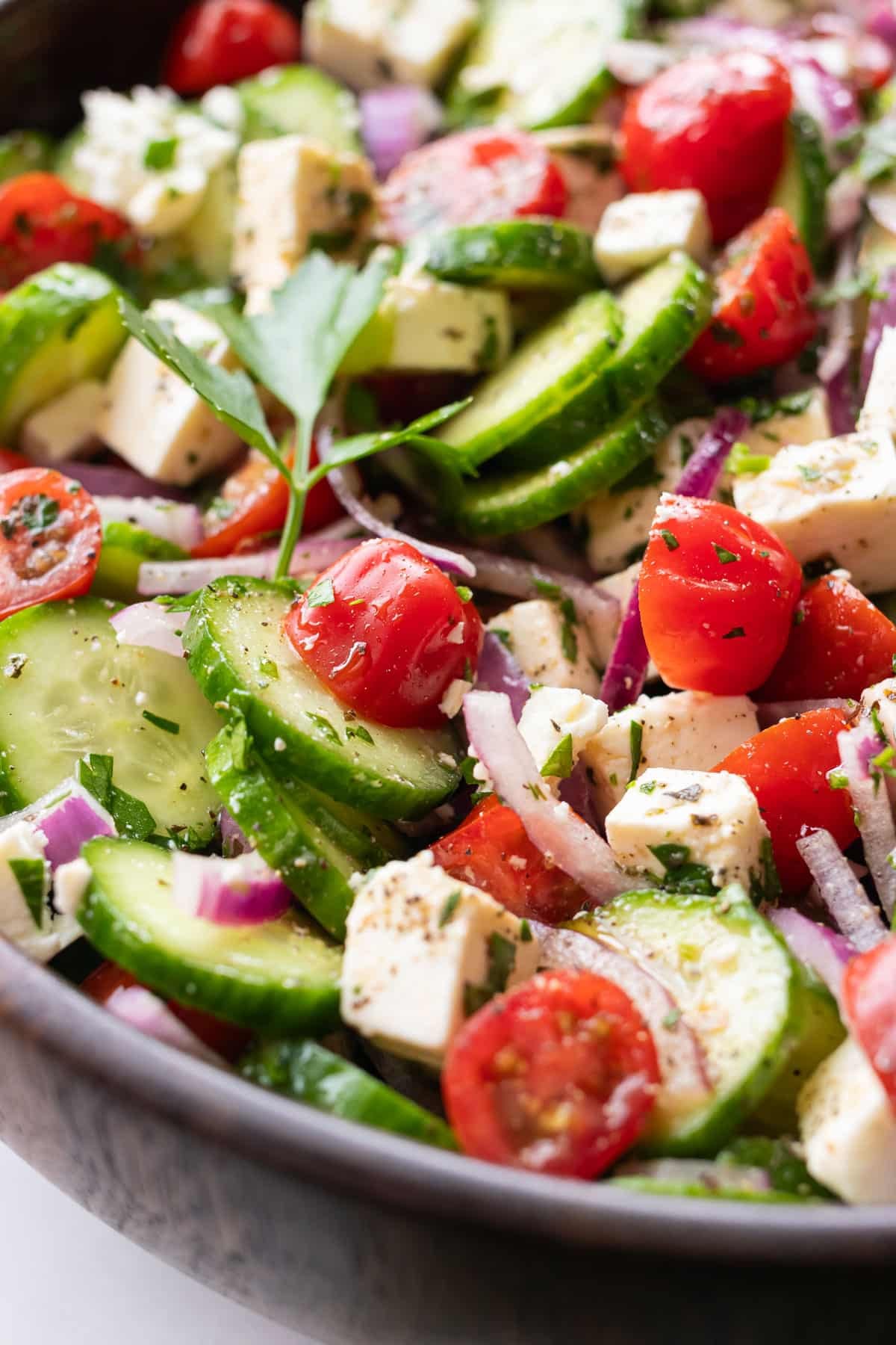 A close-up of tomatoes, cucumber slices, and feta cheese in a Greek salad.