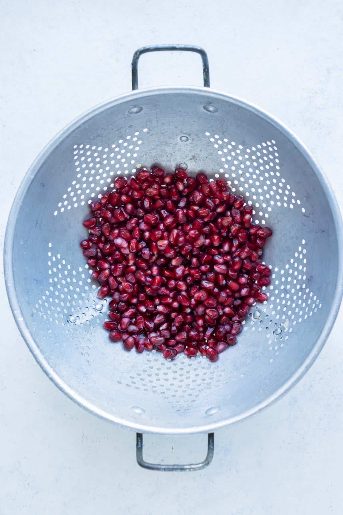 The seeds are drained from the water in a colander.