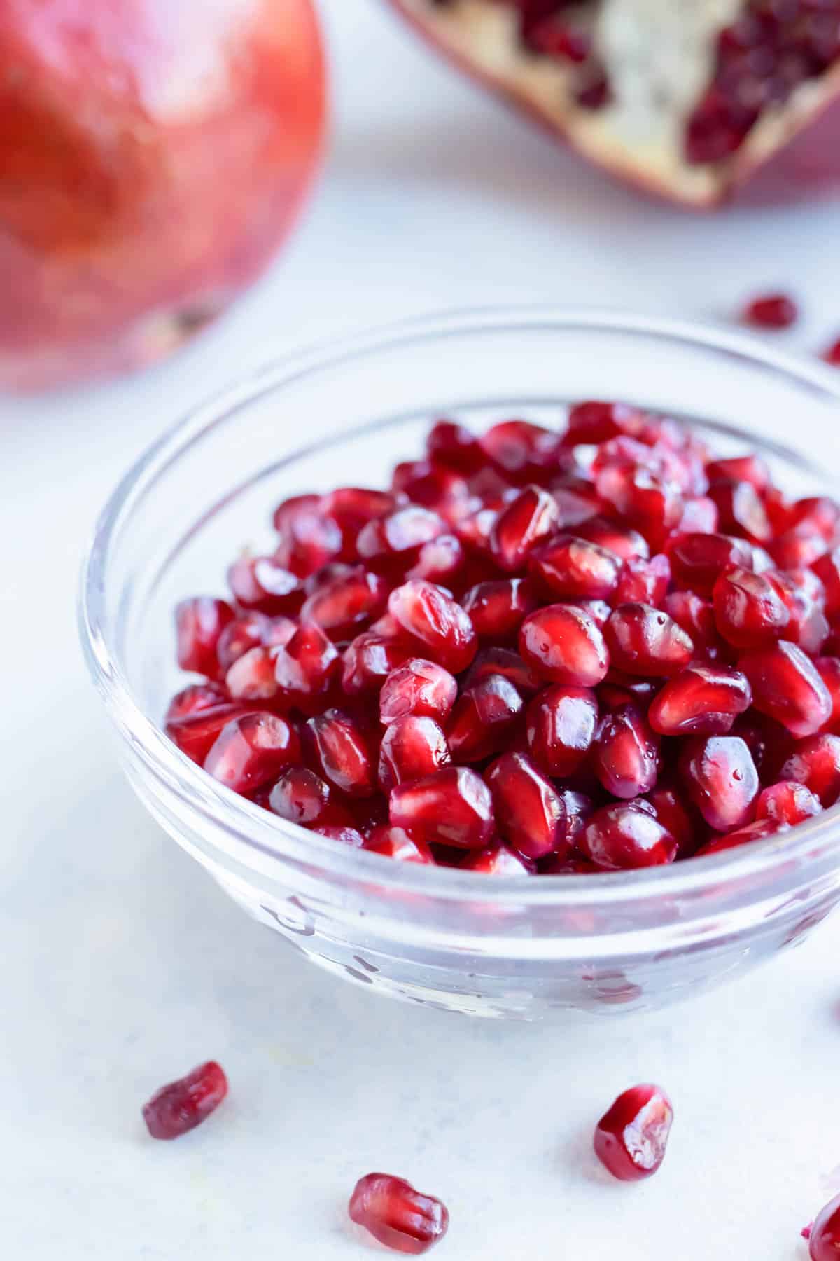 A glass bowl is used to hold the whole pomegranate seeds.