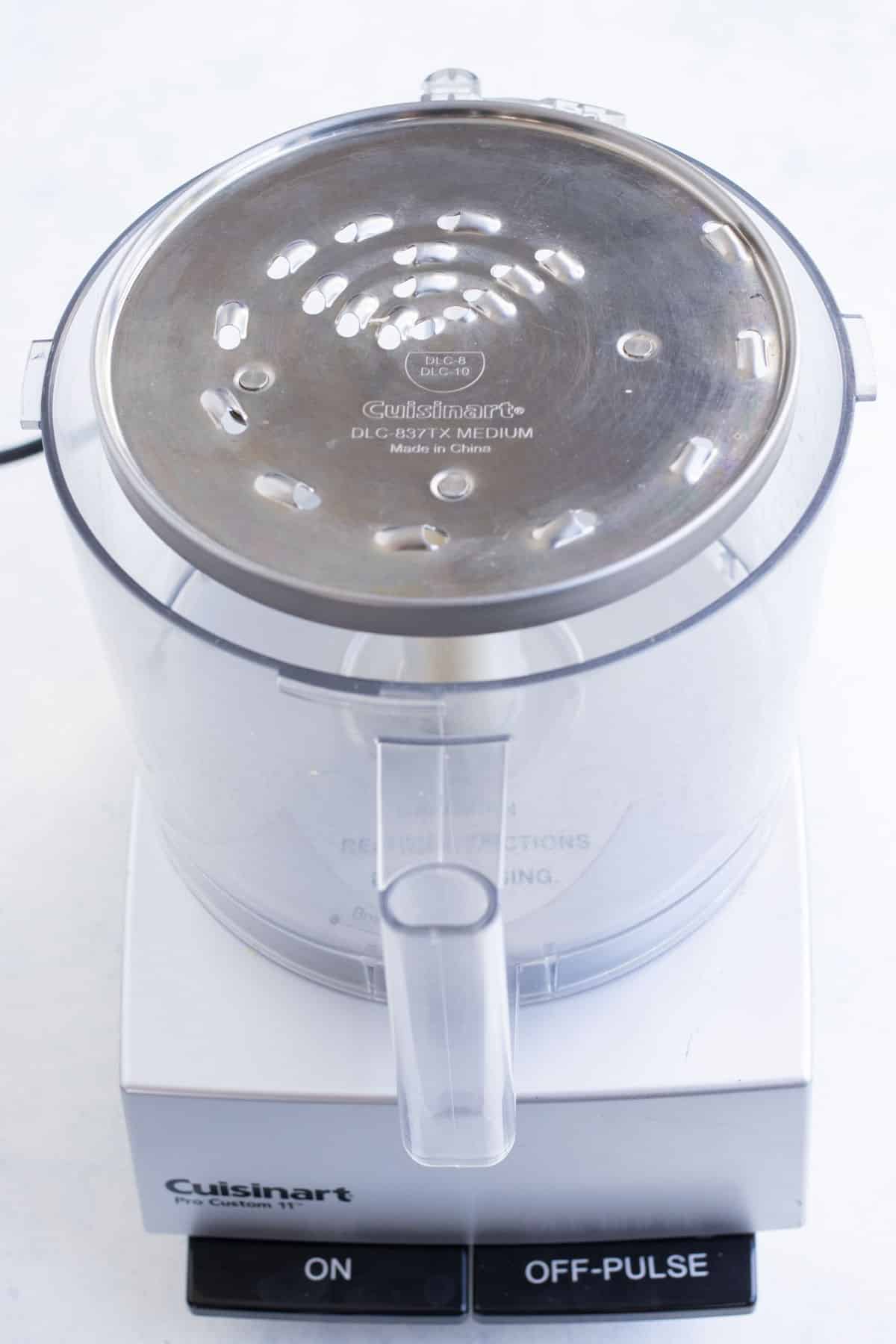 A food processor has the grating attachment ready.